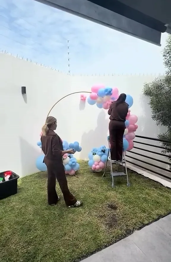 El equipo de Bloom and Dream montando un aro de globos en el jardín de una casa.